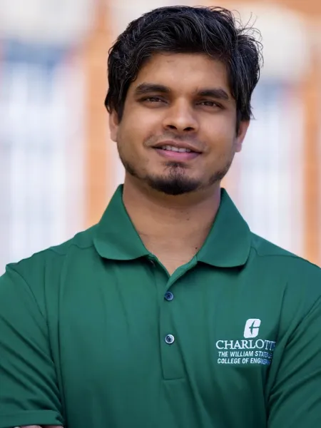Man in green collared shirt looks at camera and smiles