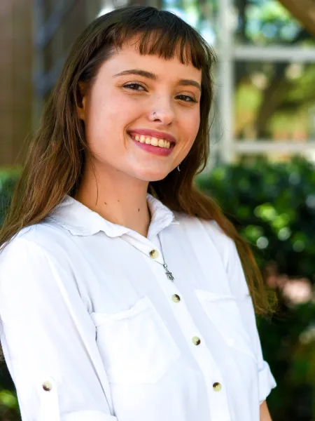 Woman in white collared shirt looks at the camera and smiles