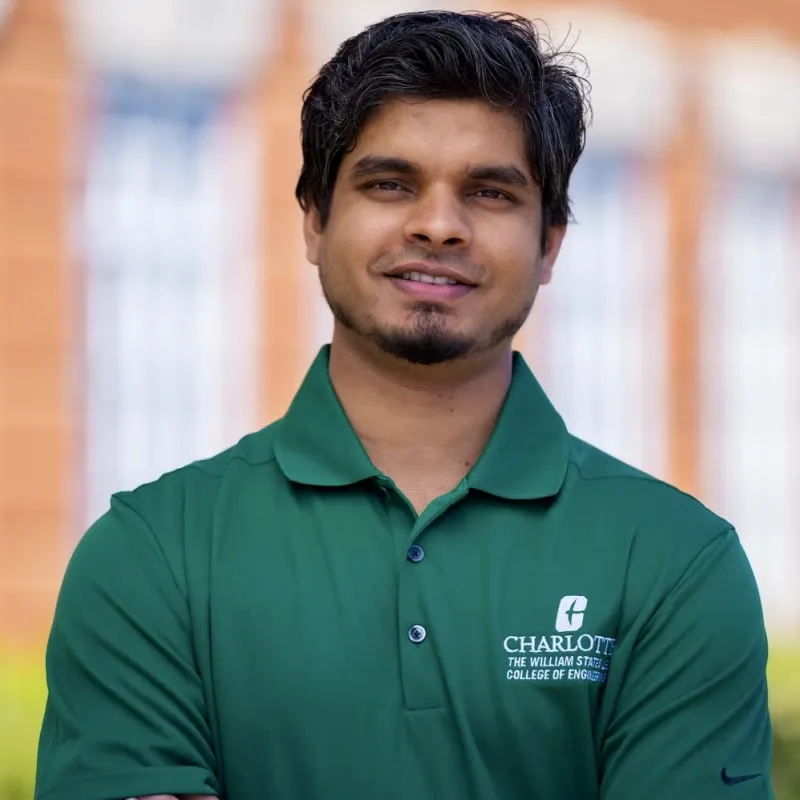 Man in green collared shirt looks at camera and smiles