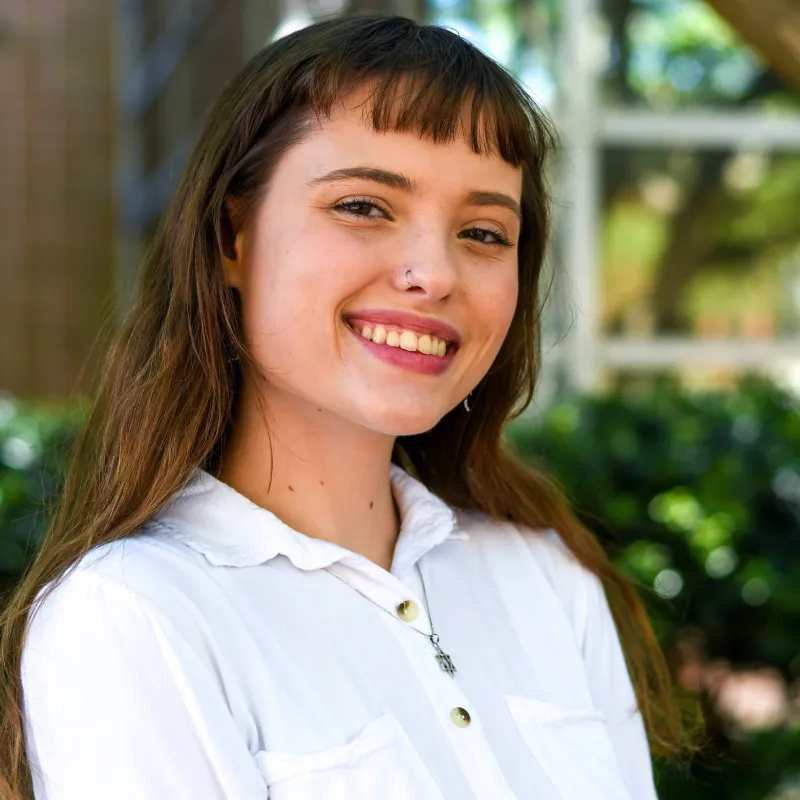 Woman in white collared shirt looks at the camera and smiles